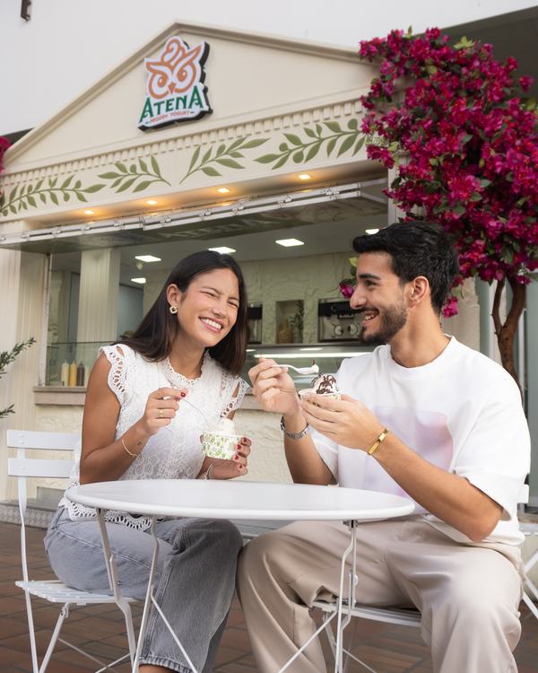 Pareja riéndose mientras comparte helado en la terraza de Atena