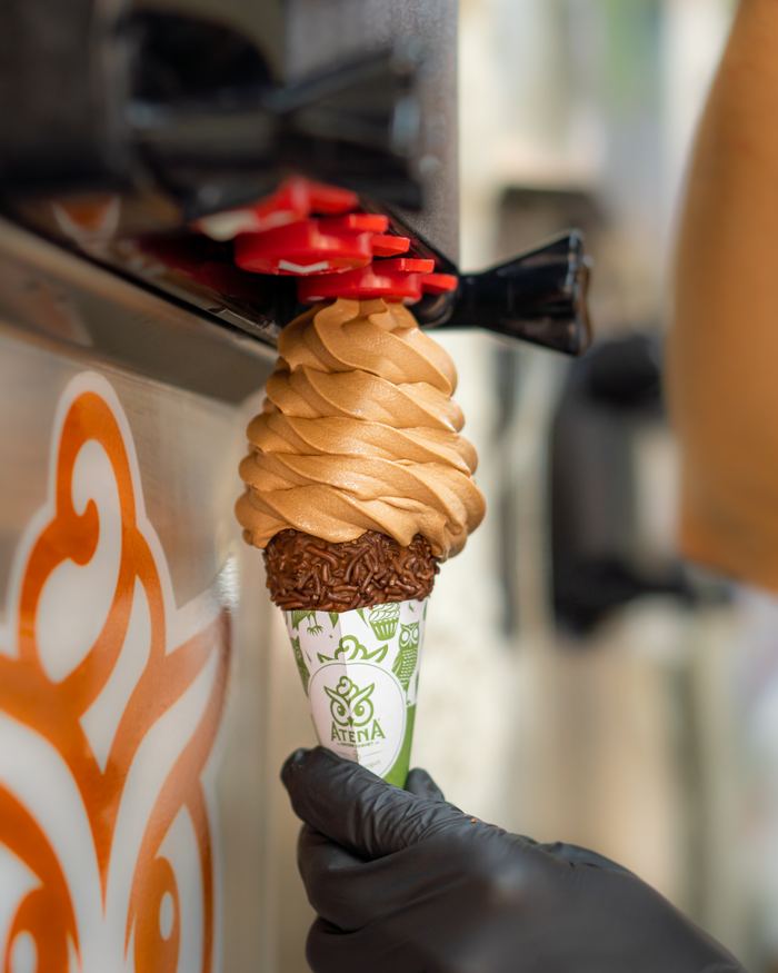 Helado de chocolate saliendo de la máquina sobre una barquilla con chispas de chocolate